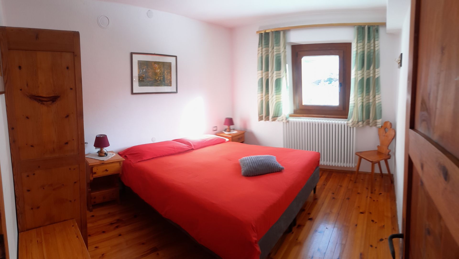 Una camera da letto con un letto rosso e un pavimento in legno.