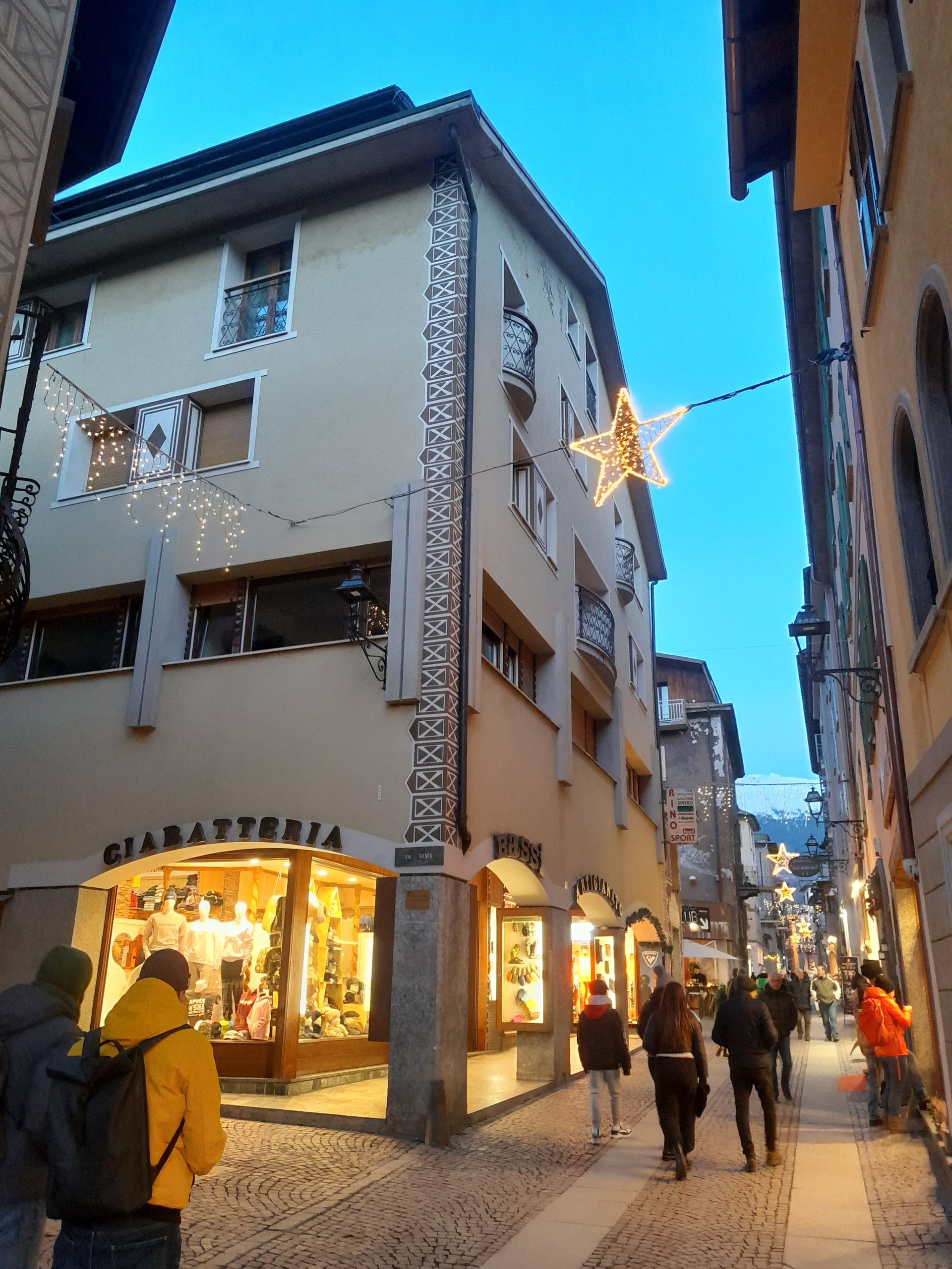 Un gruppo di persone cammina lungo una strada stretta con una stella appesa al lato di un edificio