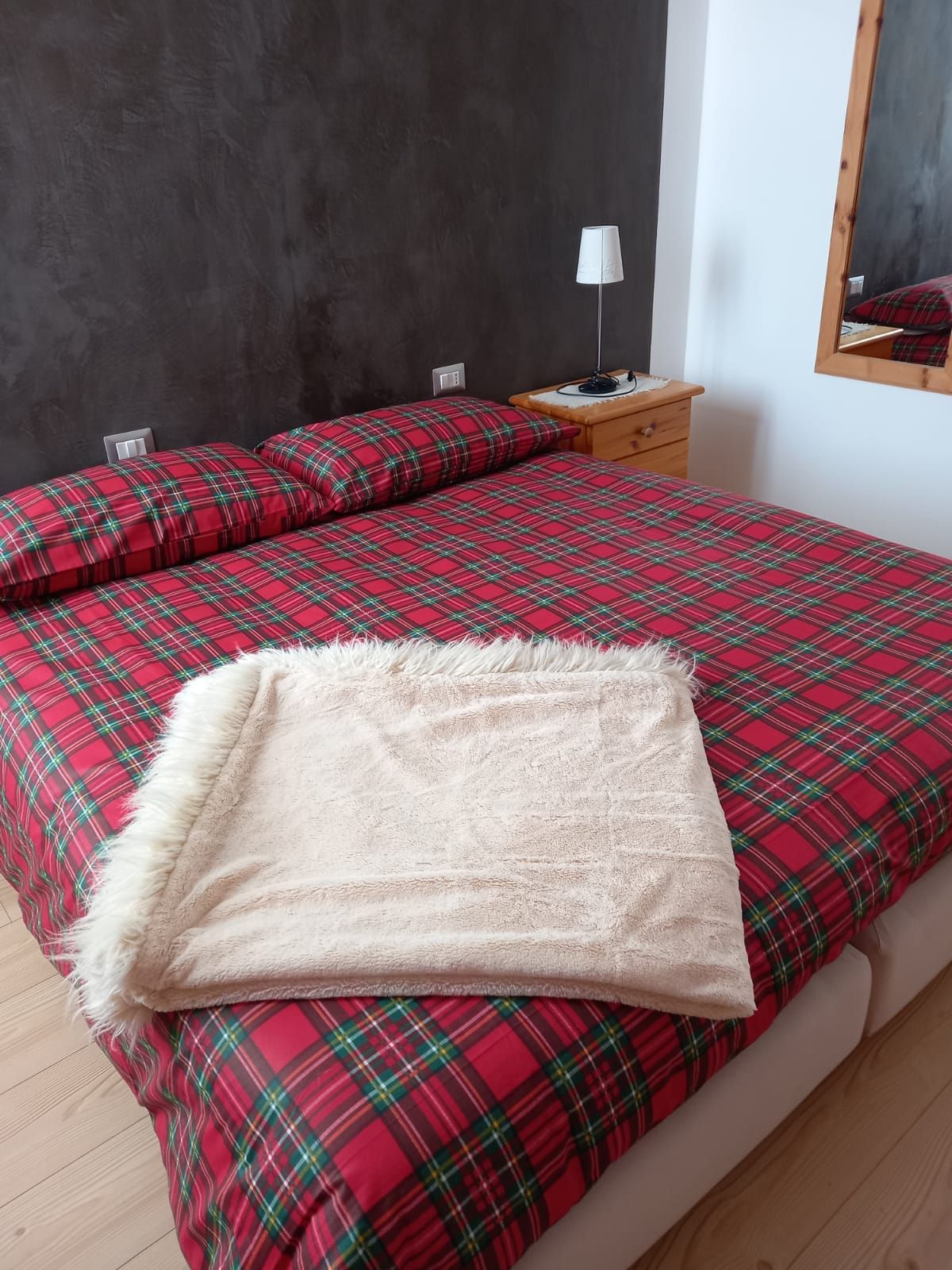 Un letto con un piumone a quadri rossi e una coperta bianca