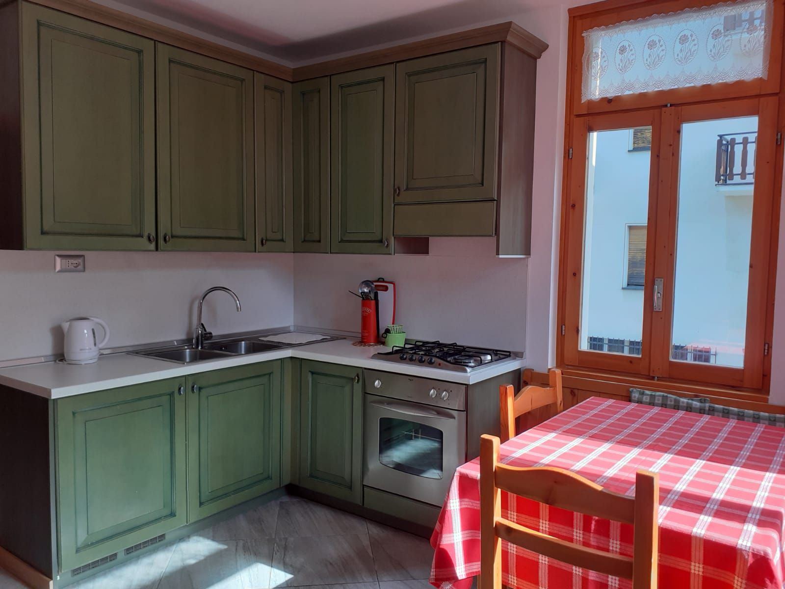 Una cucina con mobili verdi e una tovaglia rossa