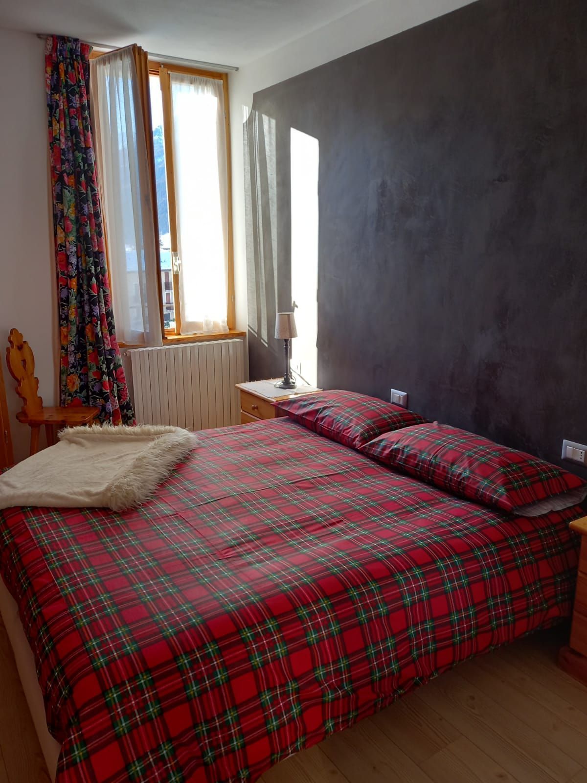 Una camera da letto con un letto, due comodini, una sedia e una finestra.