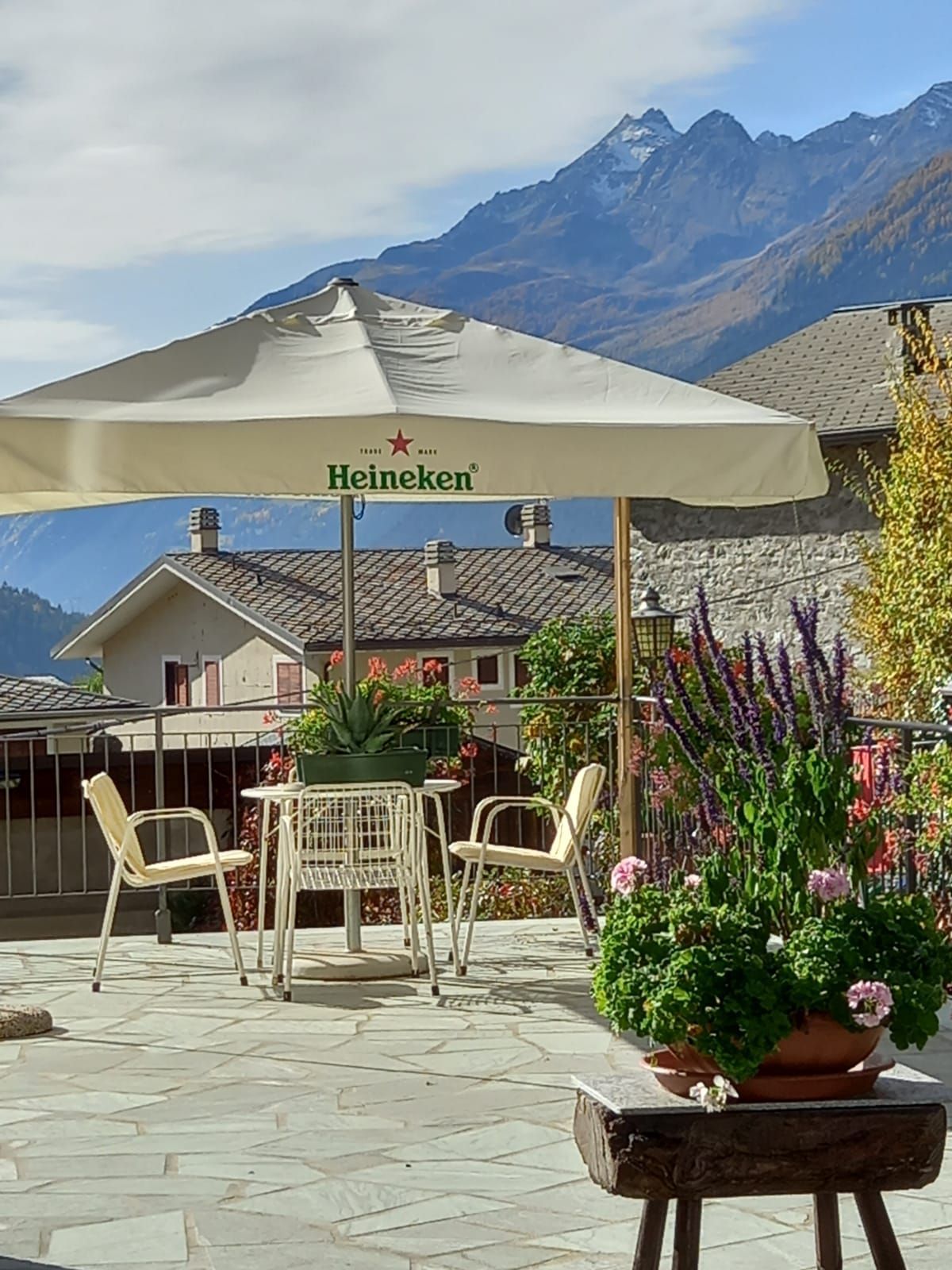 Un ombrello Heineken è appoggiato su un patio accanto a un tavolo e delle sedie.
