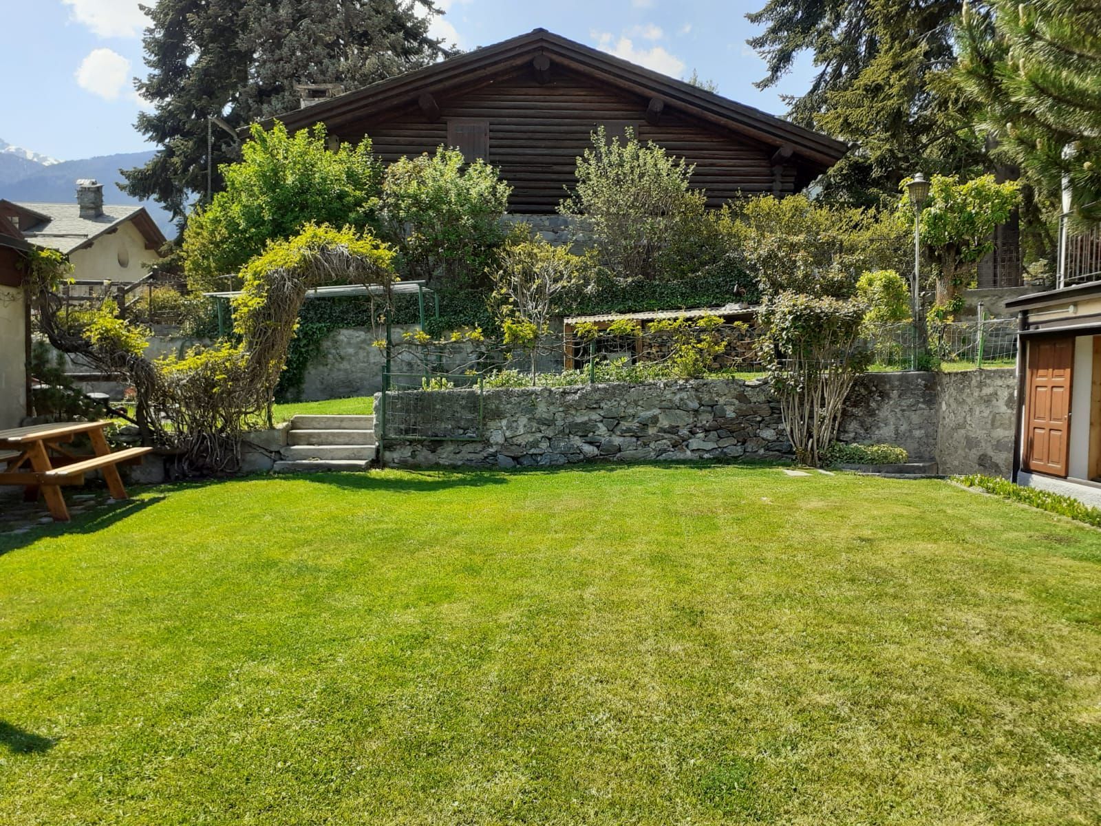 Un grande prato davanti a una casa con un tavolo da picnic.