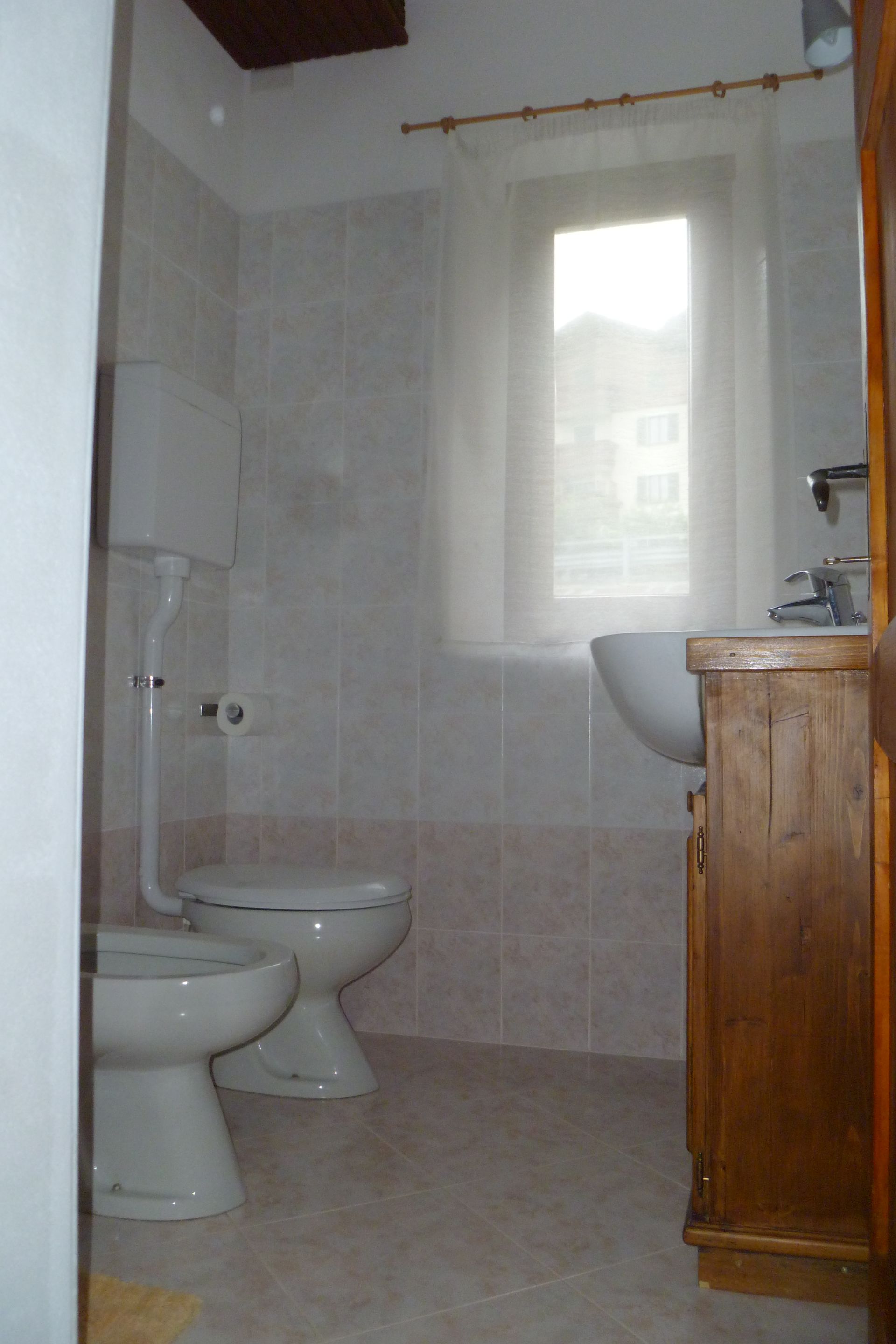 Un bagno con due water, un lavandino e una finestra