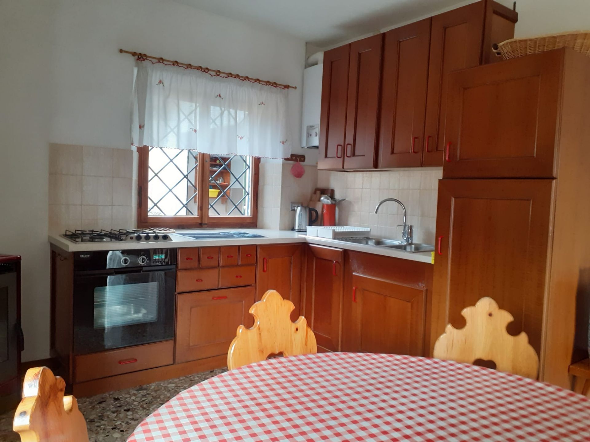 Una cucina con mobili in legno e un tavolo con una tovaglia a quadri.