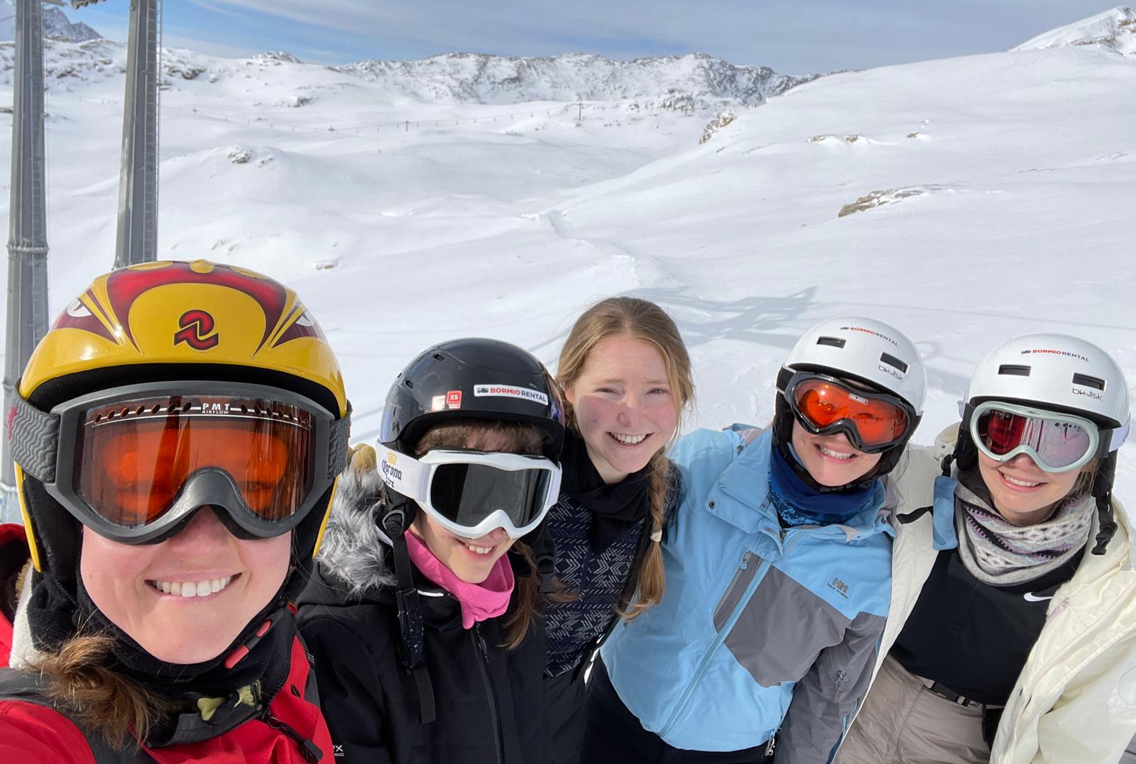 Un gruppo di persone che indossano caschi e occhiali da sci posano per una foto sulla neve.