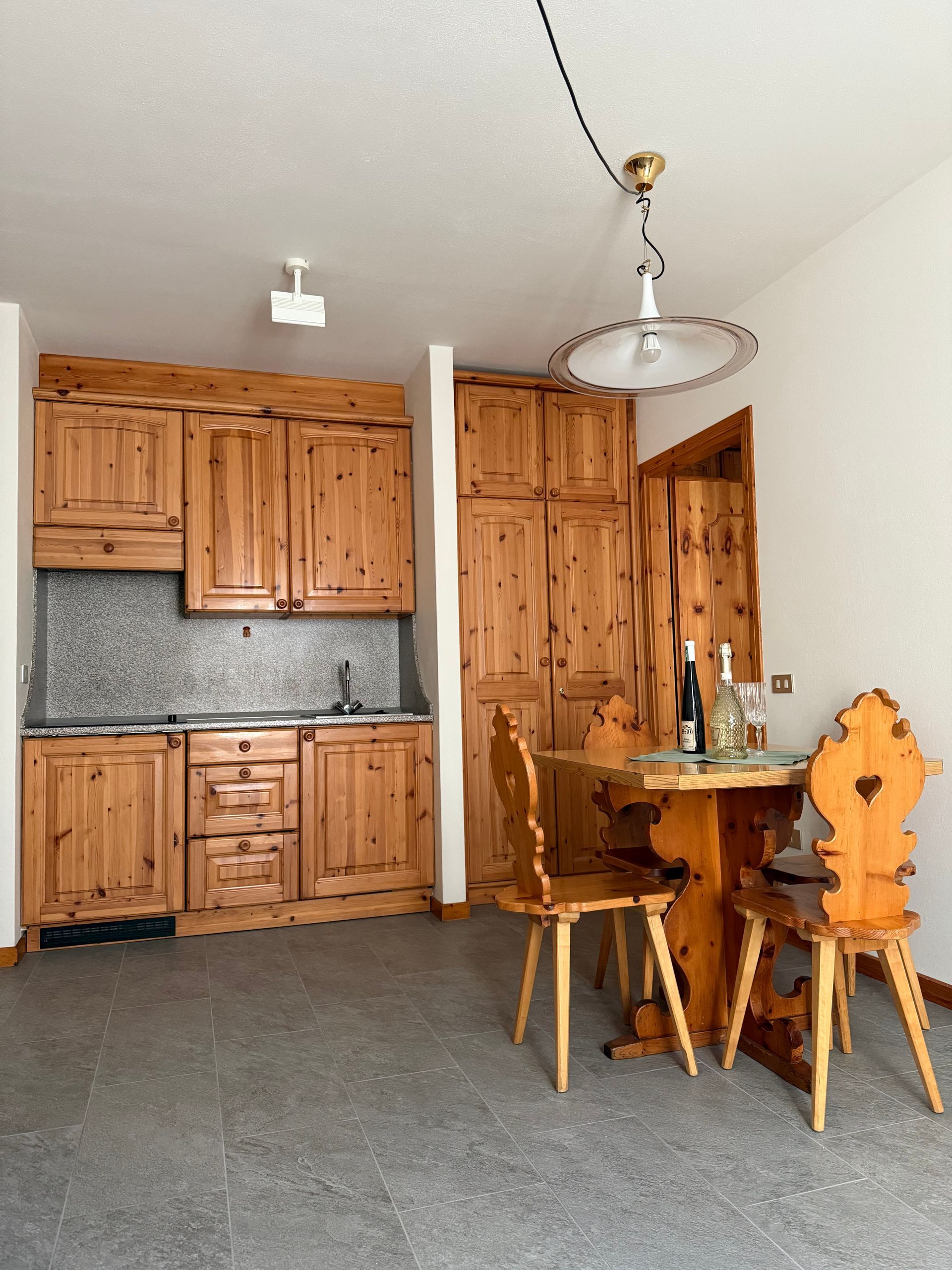 Una cucina con mobili in legno, tavolo e sedie