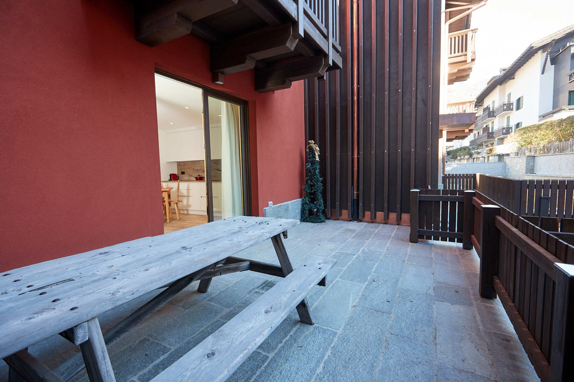Un tavolo da picnic in legno è posizionato su un patio accanto a un edificio.