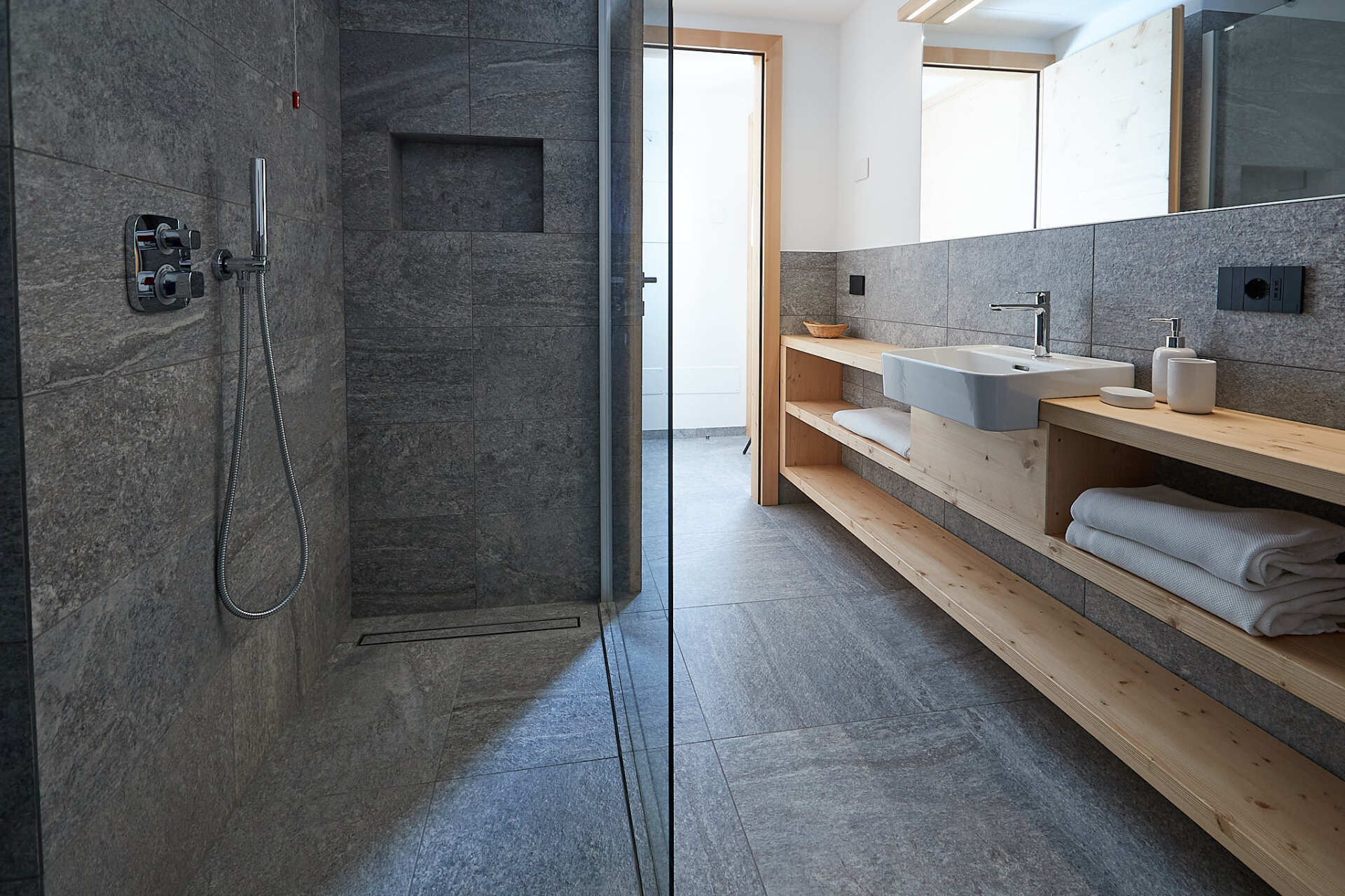 Un bagno con cabina doccia, lavandino e specchio.