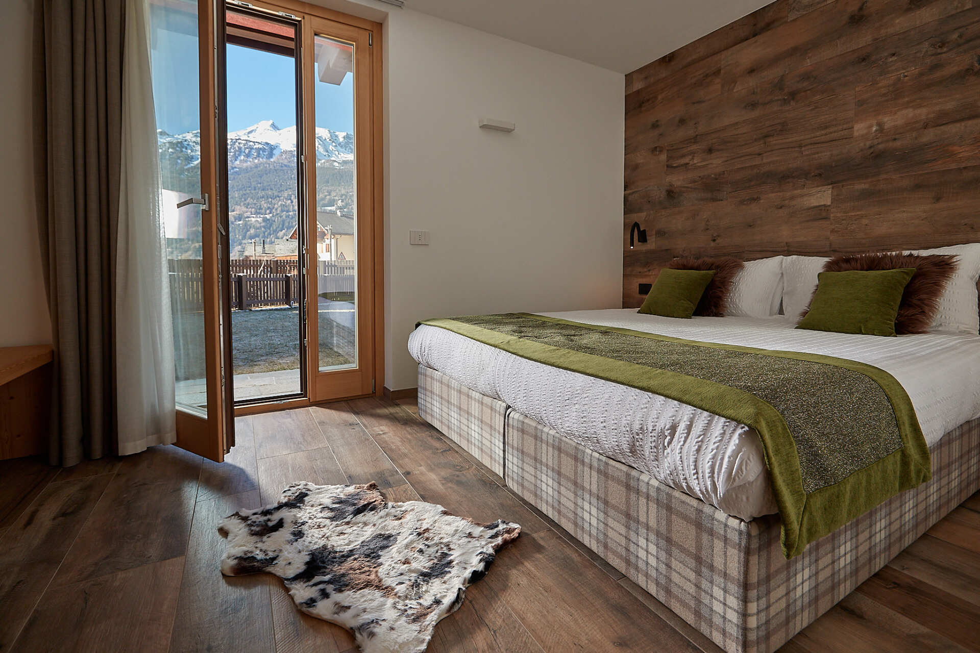 Una camera da letto con un letto grande e una porta scorrevole in vetro che conduce a un balcone.