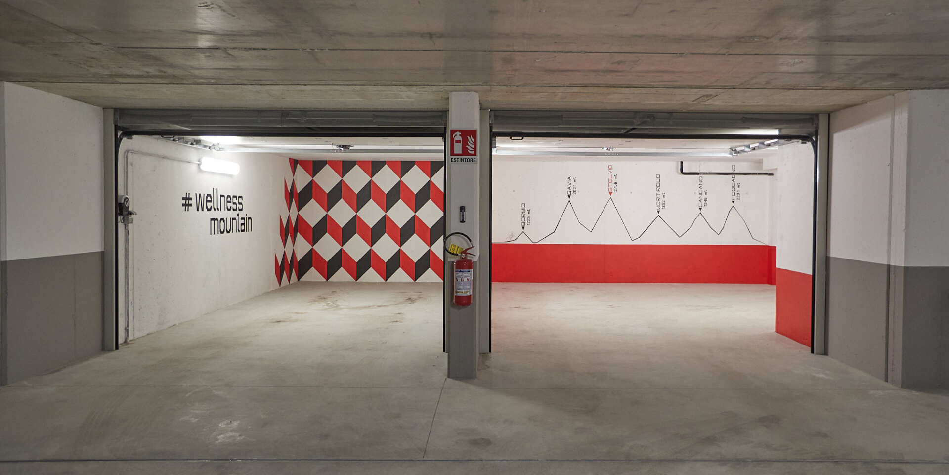 Un parcheggio vuoto con un muro a scacchi e un estintore.