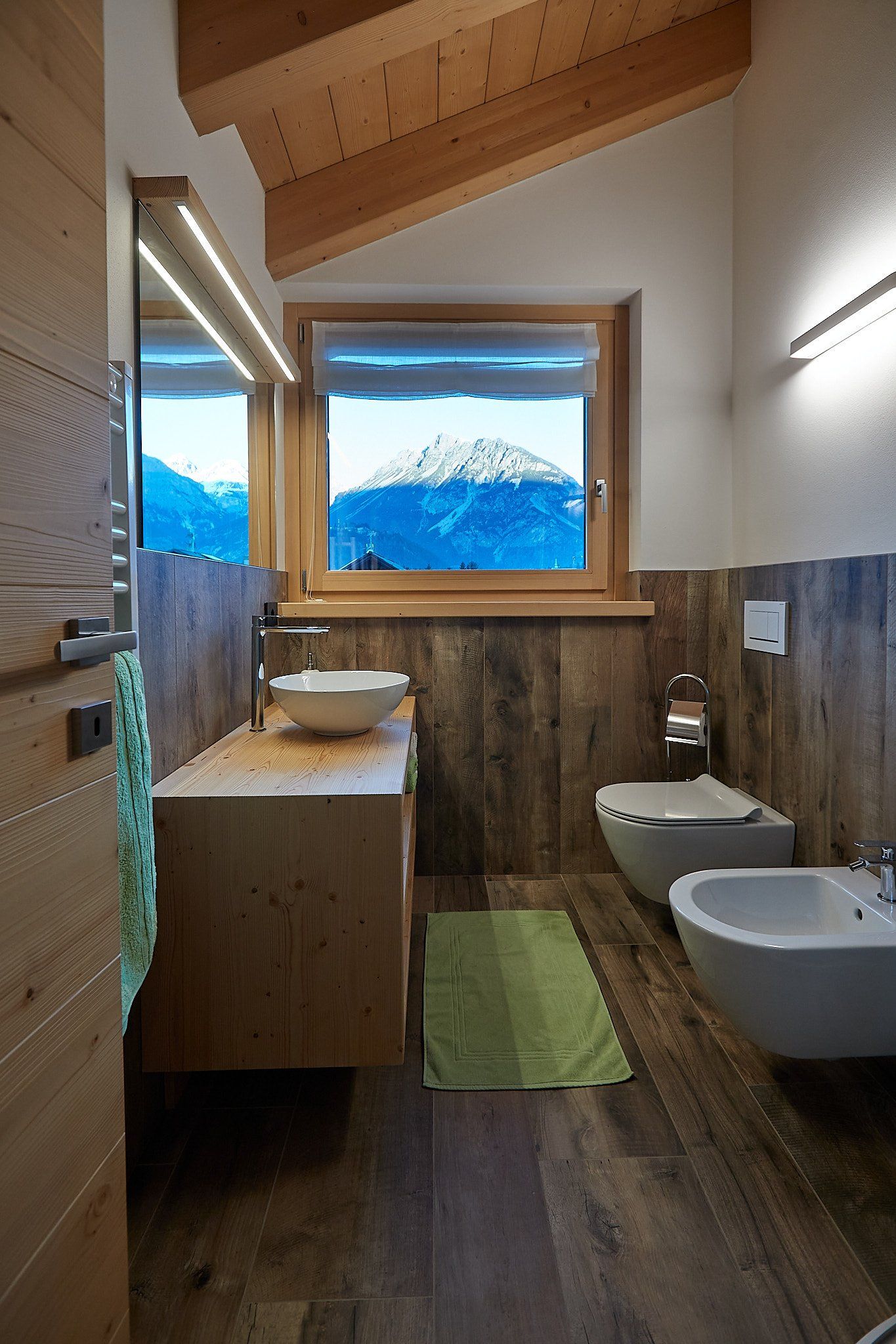 Un bagno con due lavandini, un water e una finestra con le montagne sullo sfondo.
