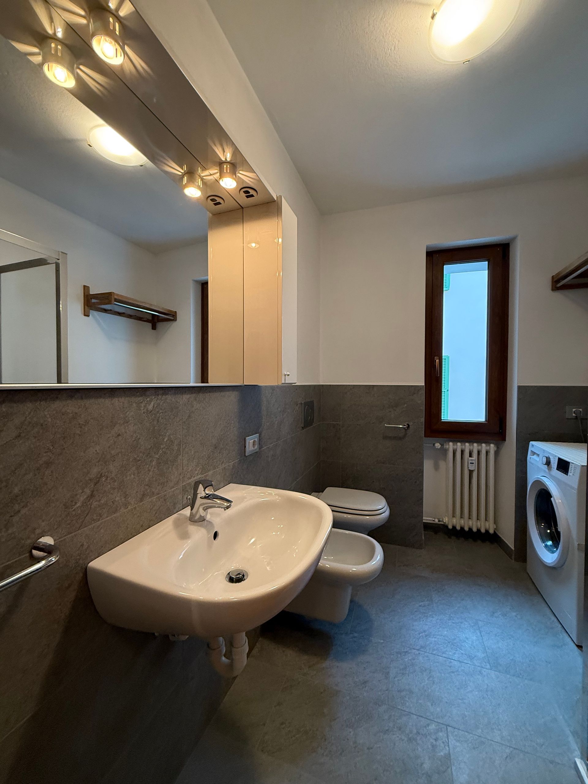 Un bagno con lavandino, wc e lavatrice