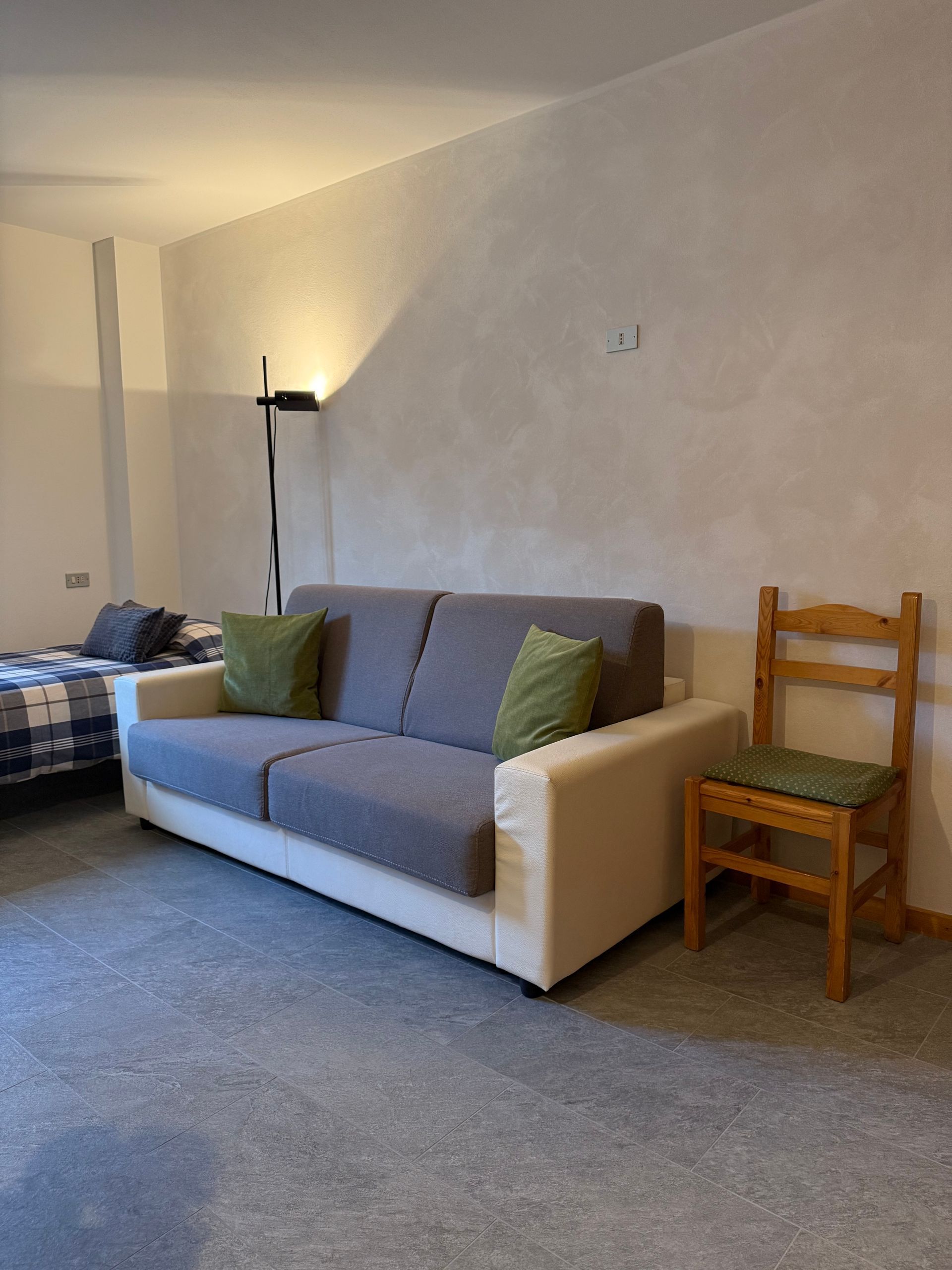 Un soggiorno con divano, sedia e letto.