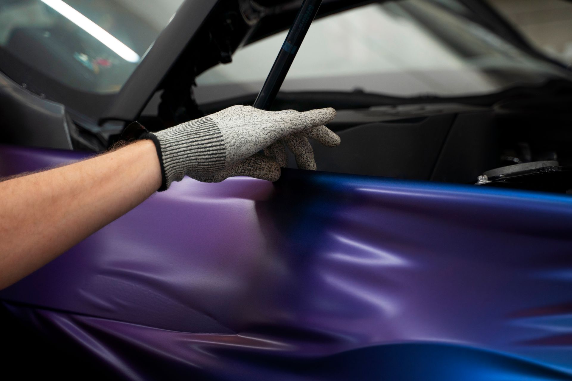 A person is wrapping a car in purple vinyl.