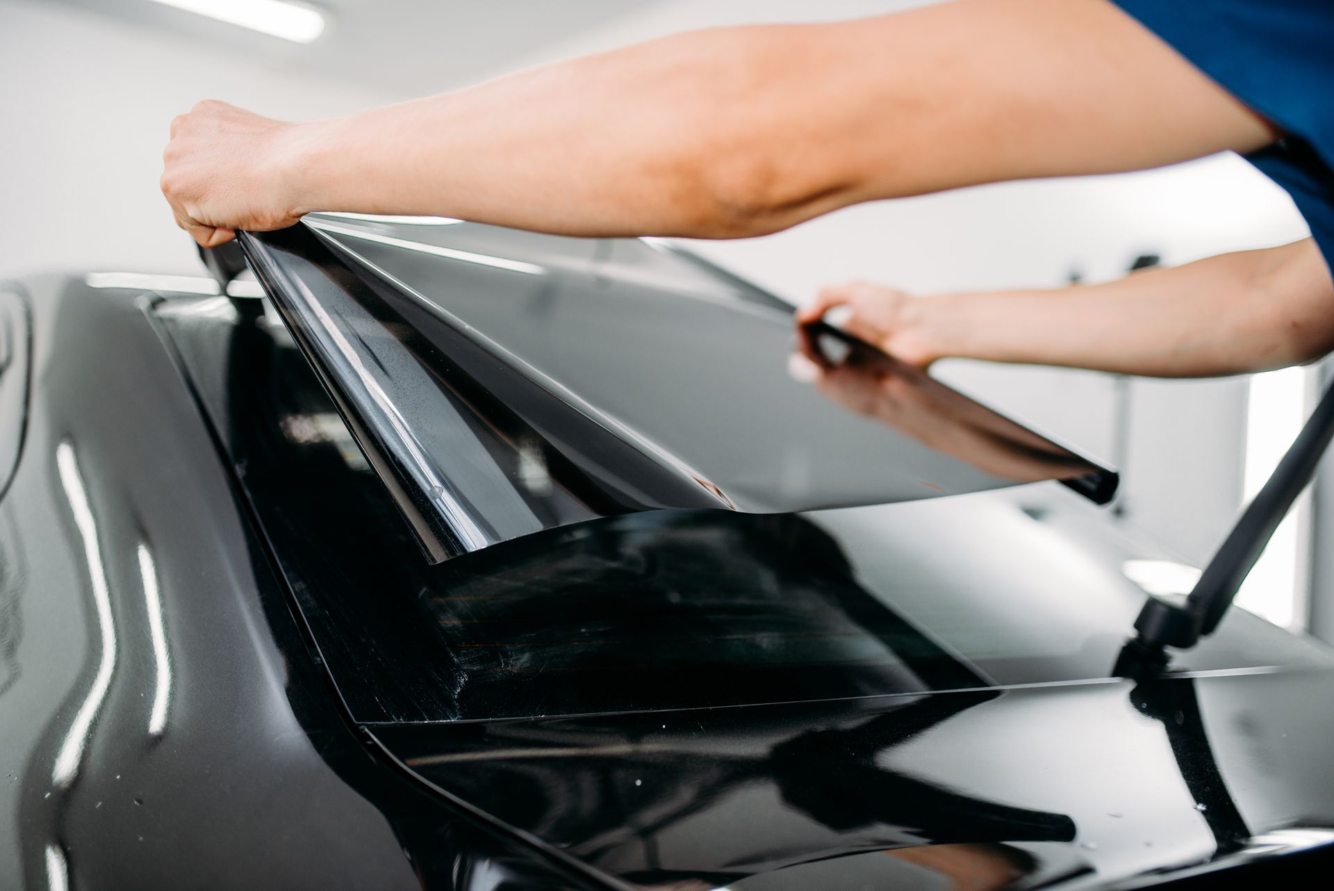 A person is applying a film to the hood of a car.