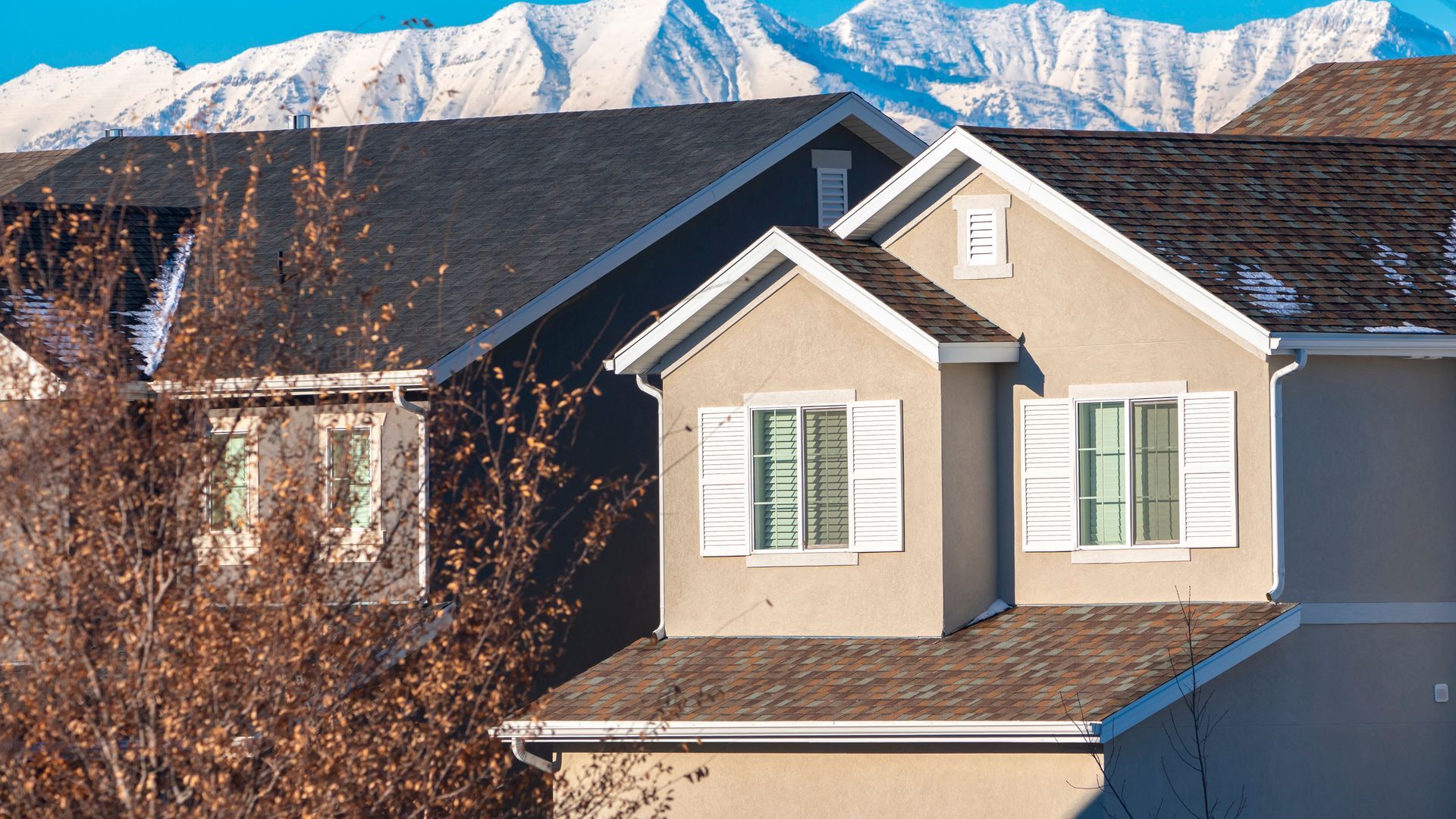 Homes in Northern Utah with snow-covered Wasatch mountains behind them in early winter