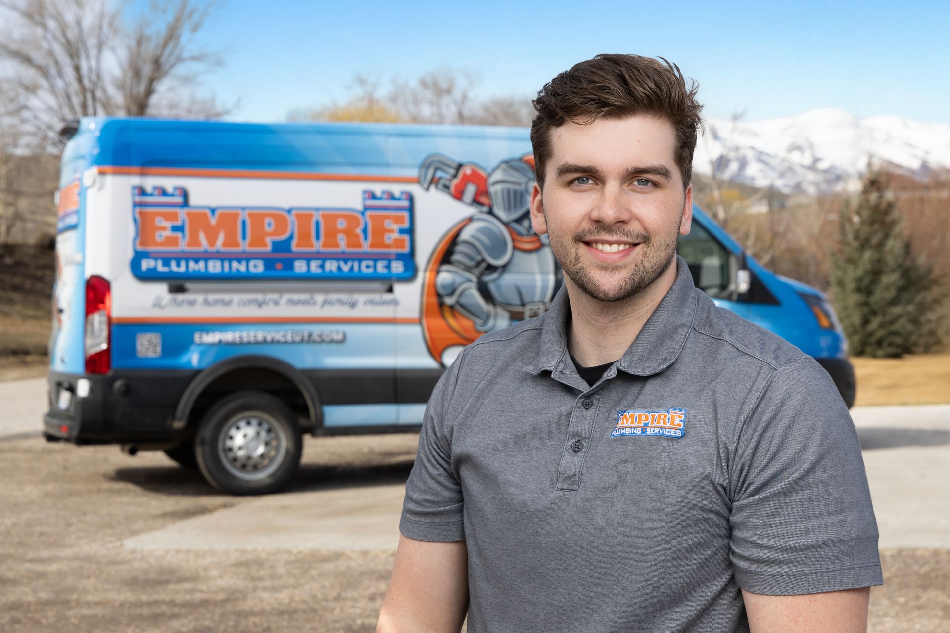 Man standing in front of a blue and orange Empire Plumbing Service van outdoors