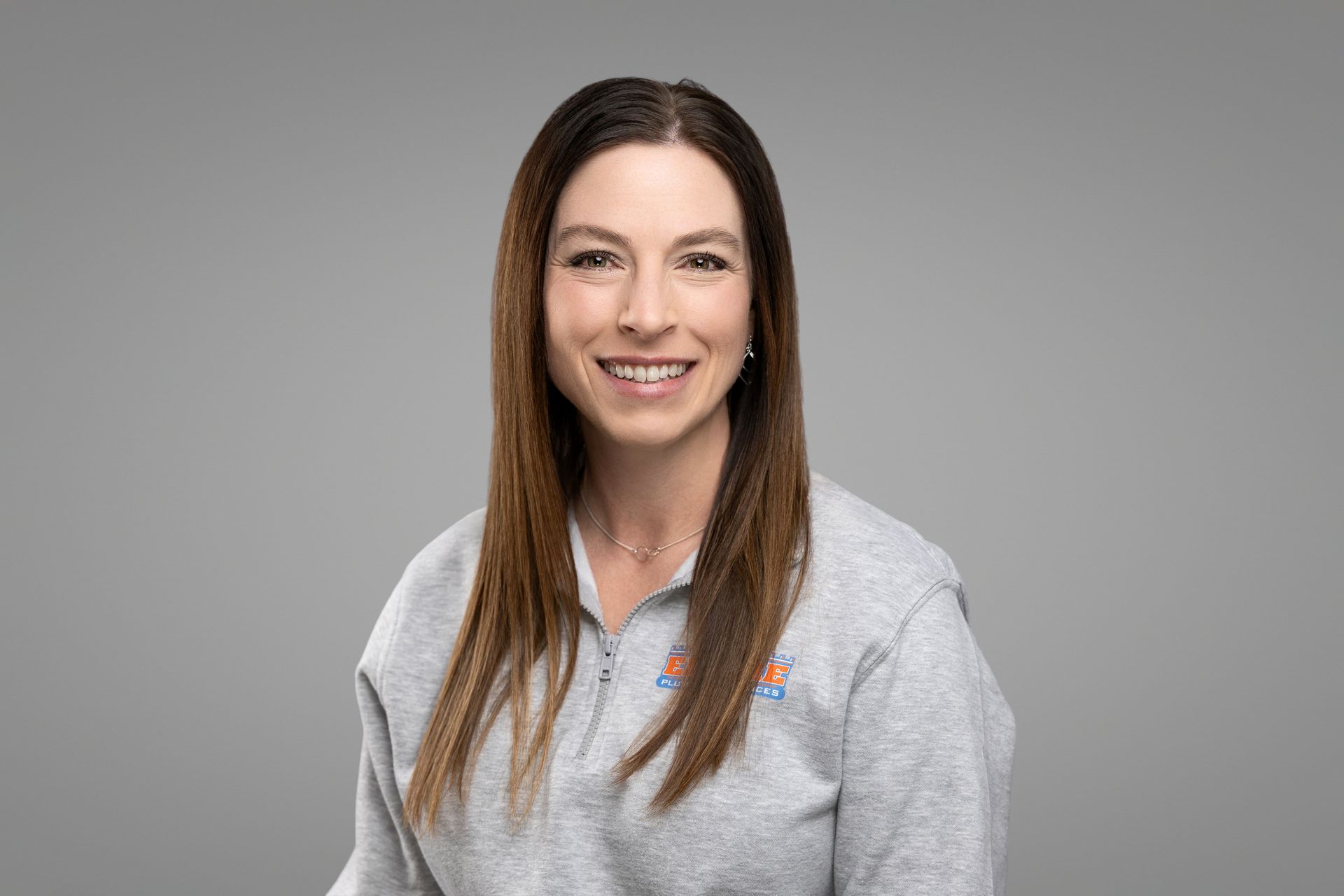 Smiling woman in a gray sweater against a plain gray background