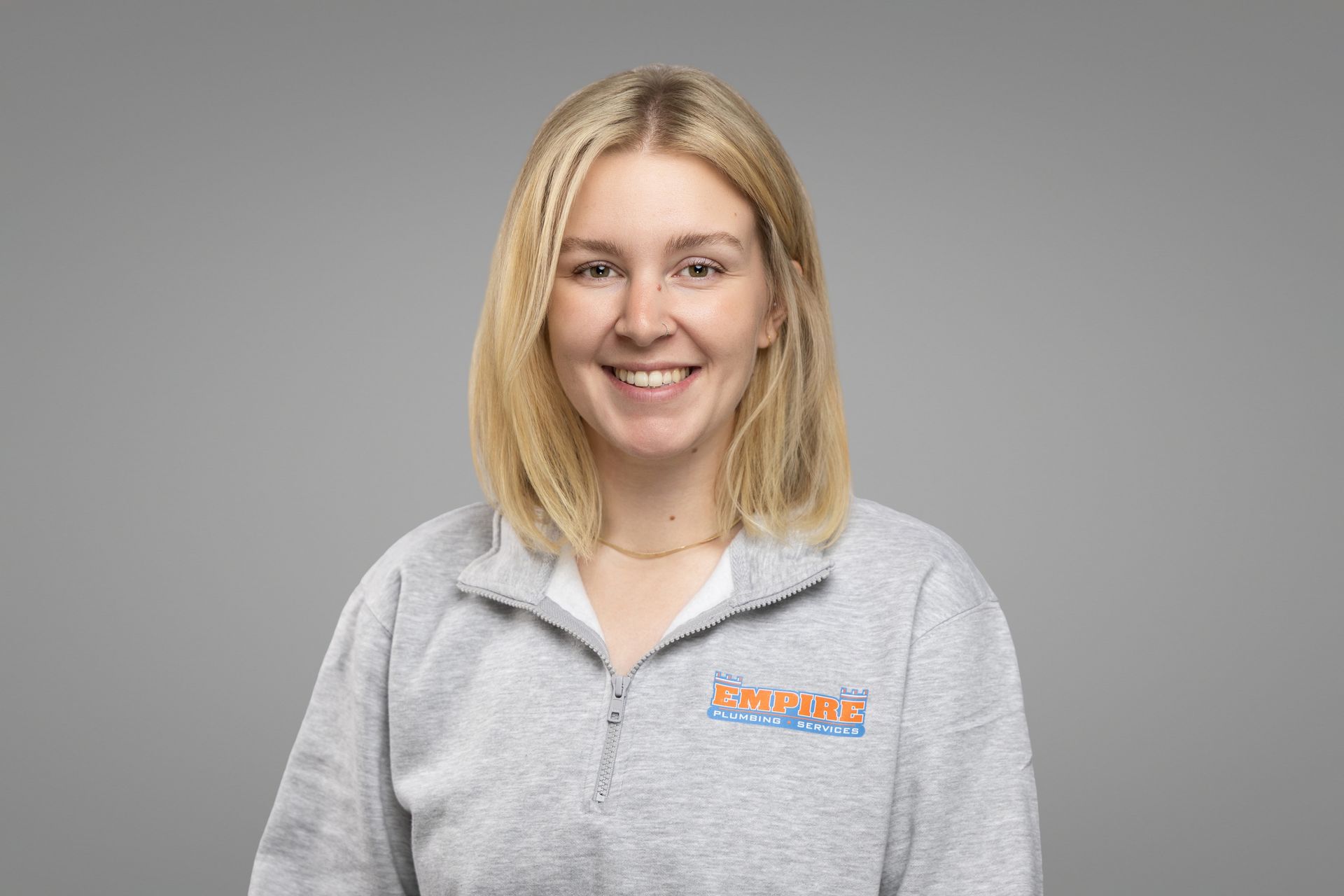 Smiling woman in a gray quarter-zip shirt against a plain gray background