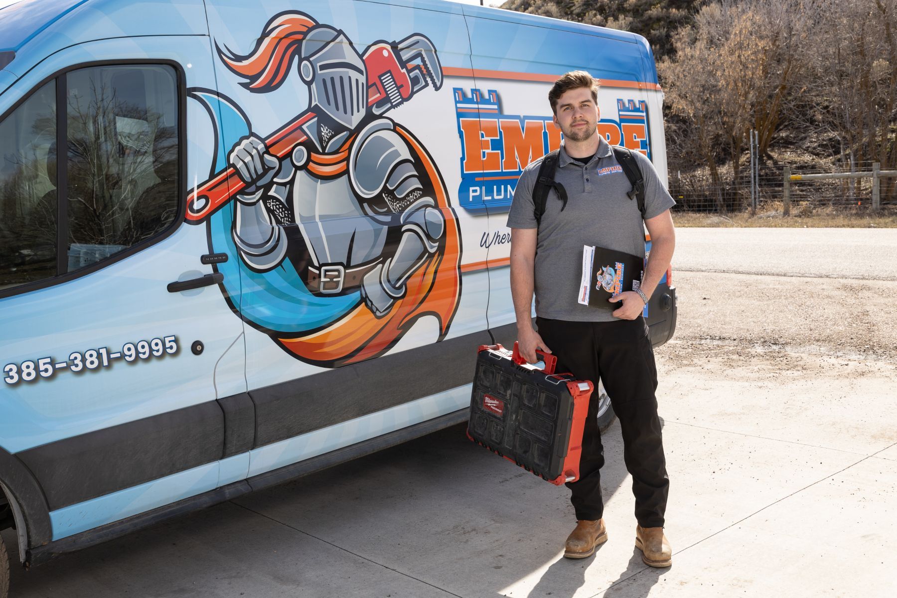 Service technician talking with a homeowner beside a marked service van in a suburban driveway.