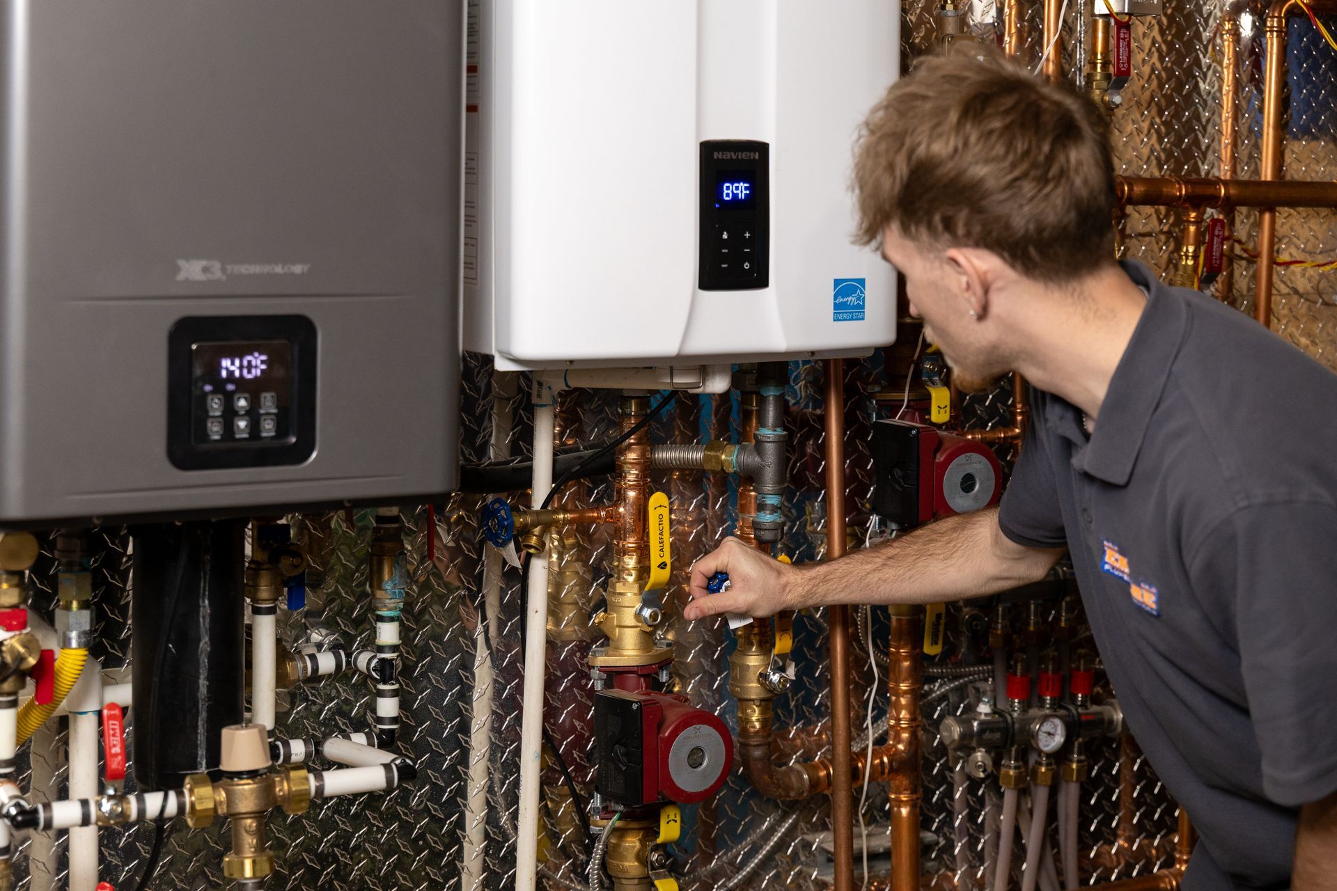Technician inspecting boiler and exposed pipes in a mechanical room