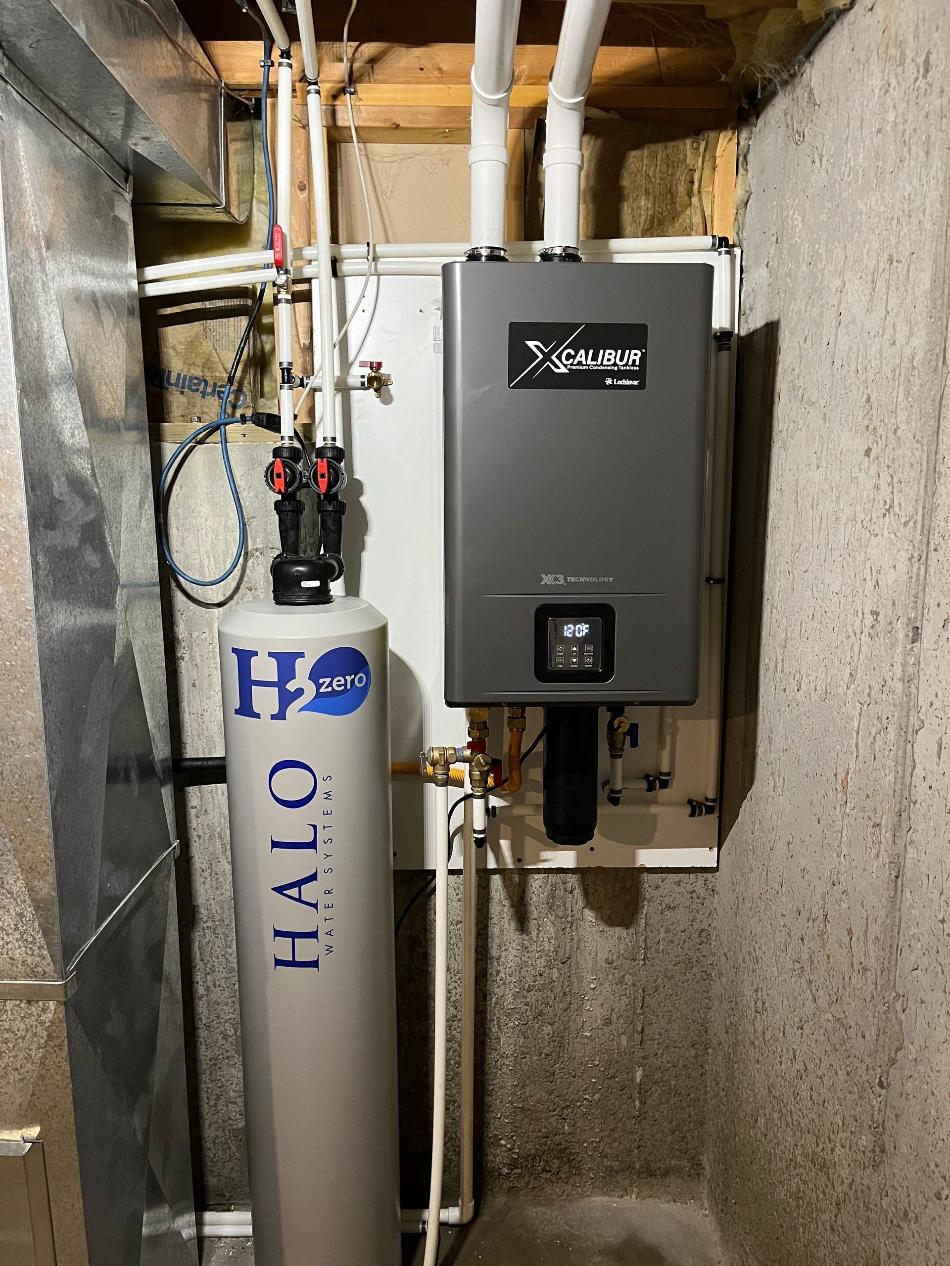 Water heater and water softener installed on a concrete basement wall.