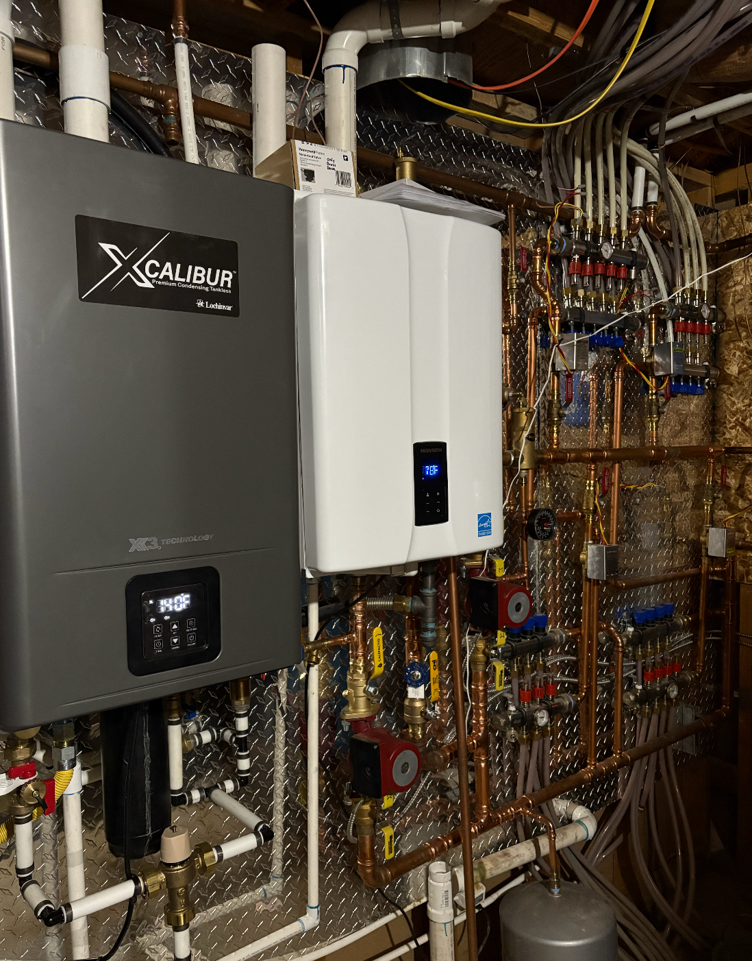 Two water heaters mounted on a wall, with extensive copper piping and valves visible.
