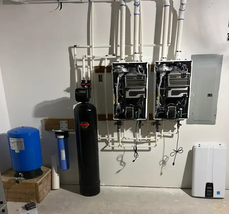 Two open tankless water heaters beside a water softener, whole-house filter and expansion tank