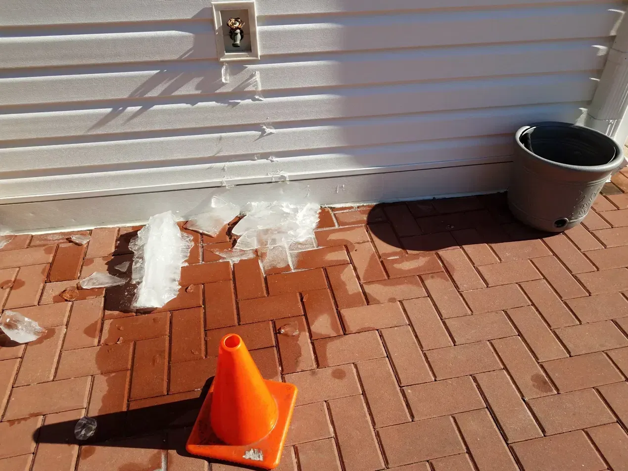 Outdoor faucet encased in ice with a garden hose still connected