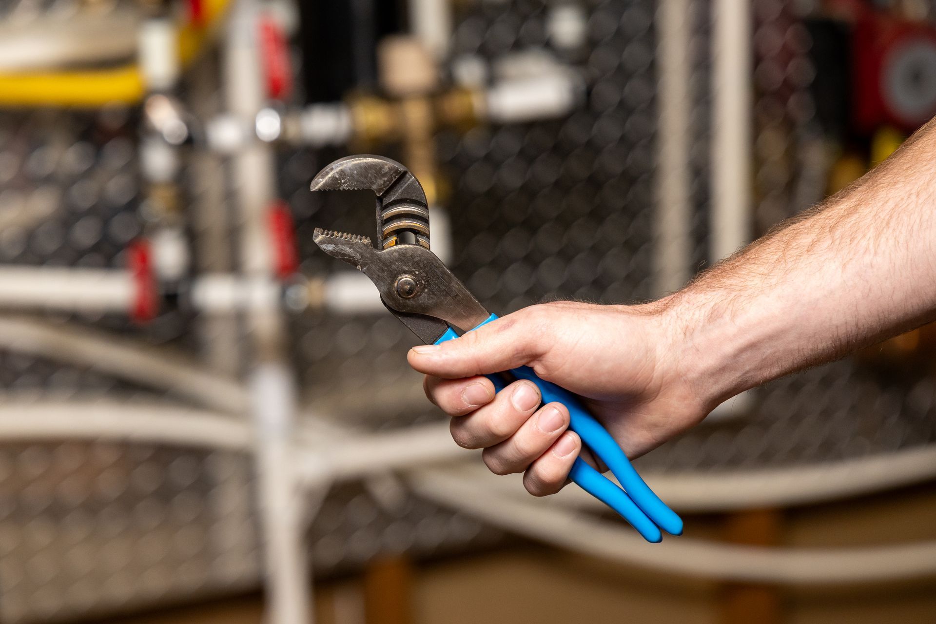 Plumber holding tongue-and-groove pliers in a home mechanical room