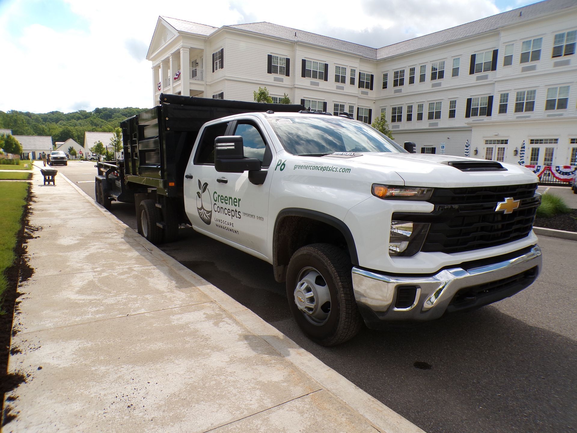 White Chevrolet work truck with a flatbed parked beside a building on a paved road
