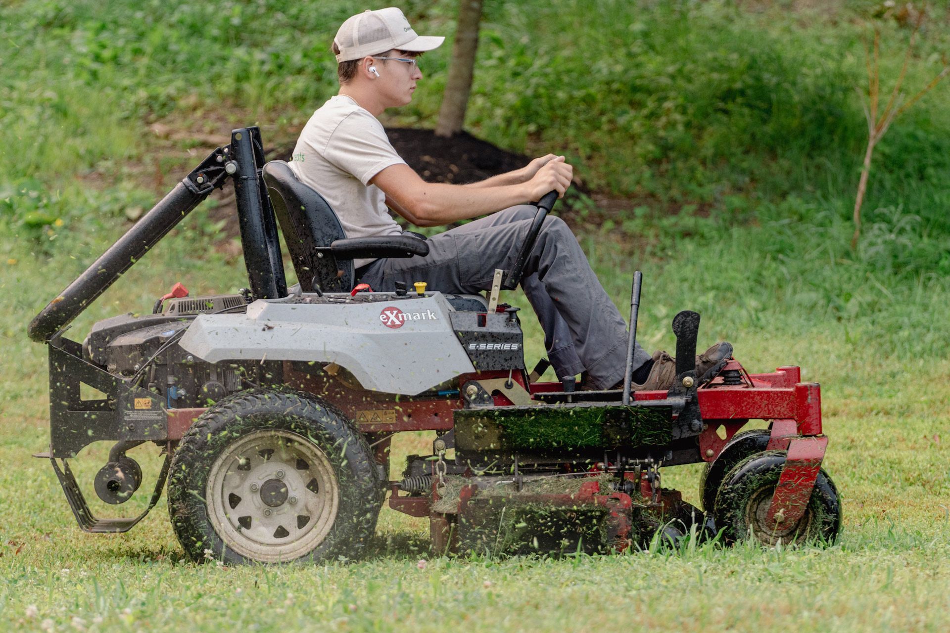 Man riding a red mower across a grassy field