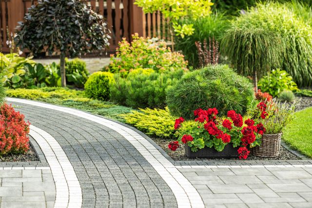 Curved garden path beside colorful flower beds and trimmed shrubs in a landscaped park