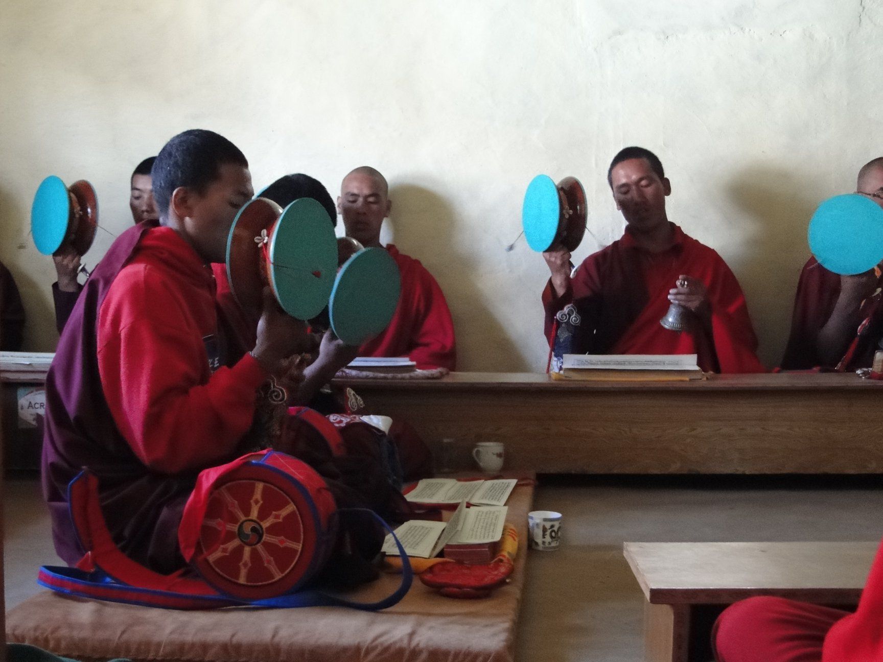 Group seated in a classroom, holding colorful round fans or mirrors during a lesson.
