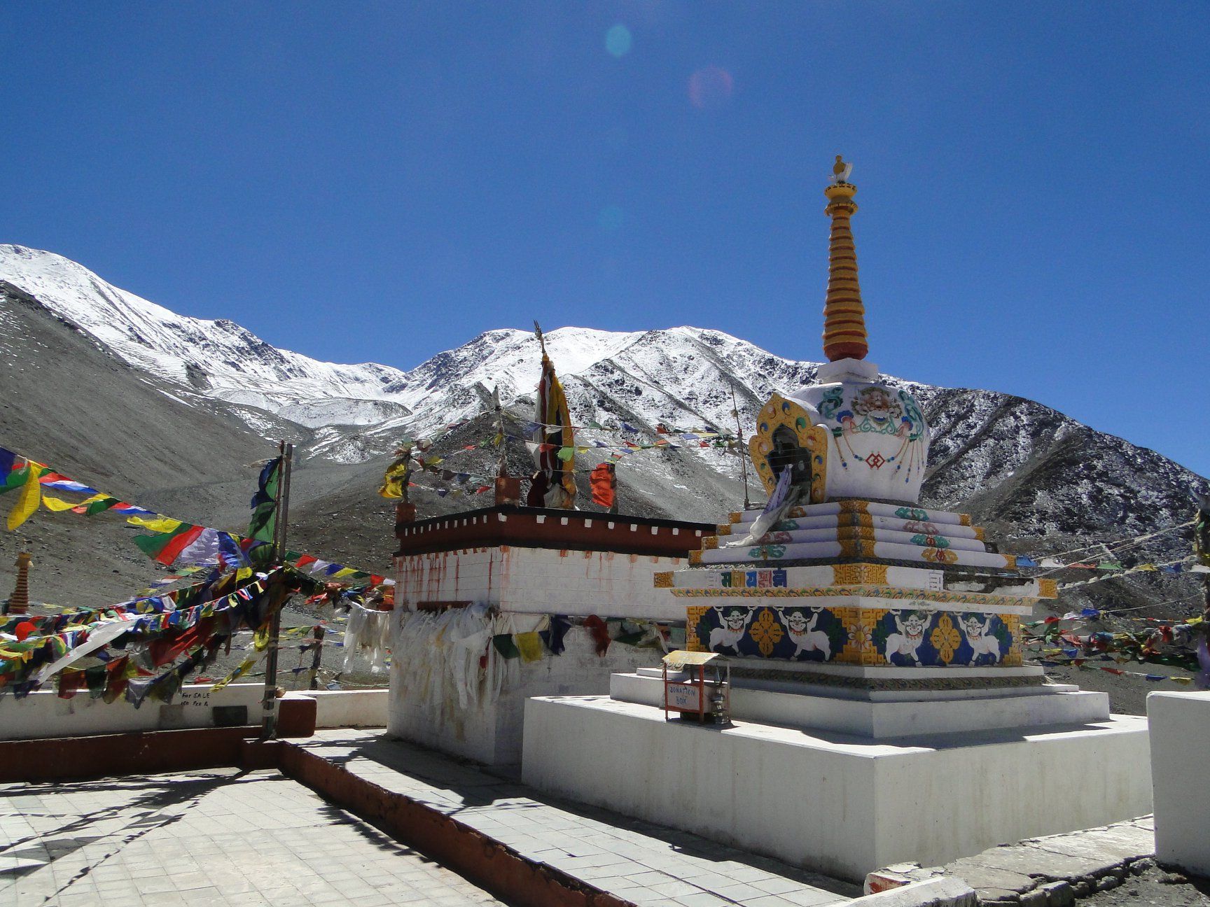 Buddhist stupa and prayer flags in a snowy mountain landscape under a clear blue sky
