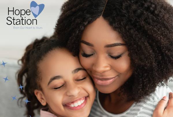 A woman and a little girl are hugging each other and smiling.