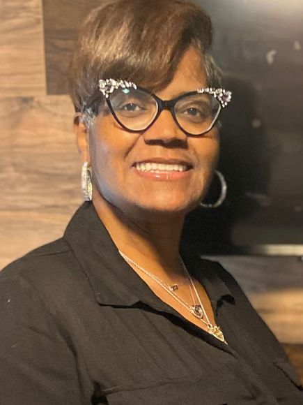 A woman wearing glasses and a black shirt is smiling for the camera.