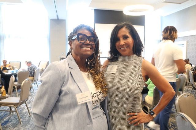 Two women are posing for a picture in a conference room.