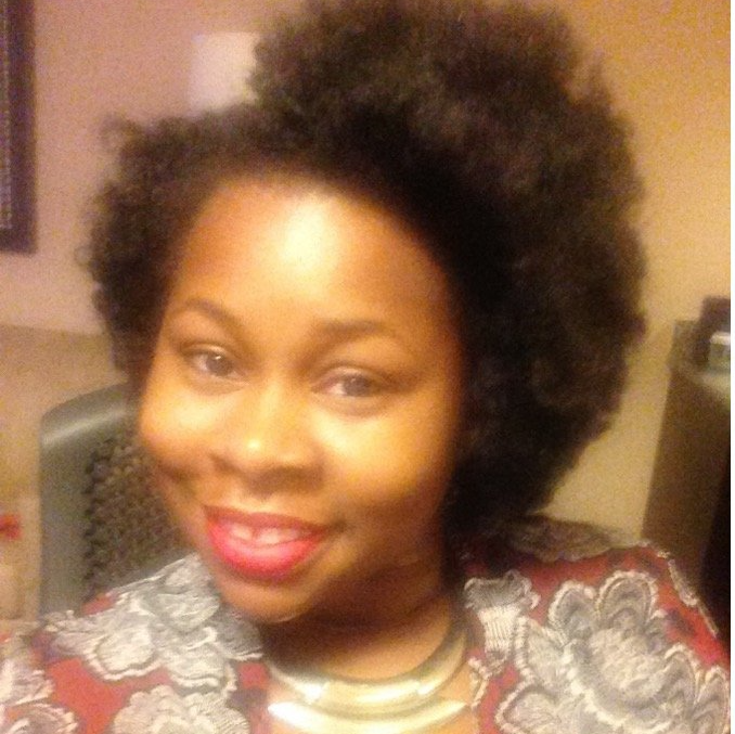A woman with afro hair is smiling for the camera
