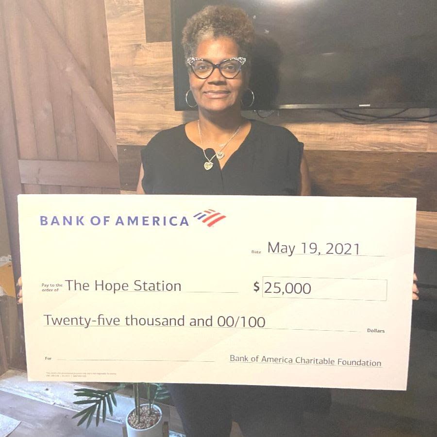 A woman is holding a bank of america check.