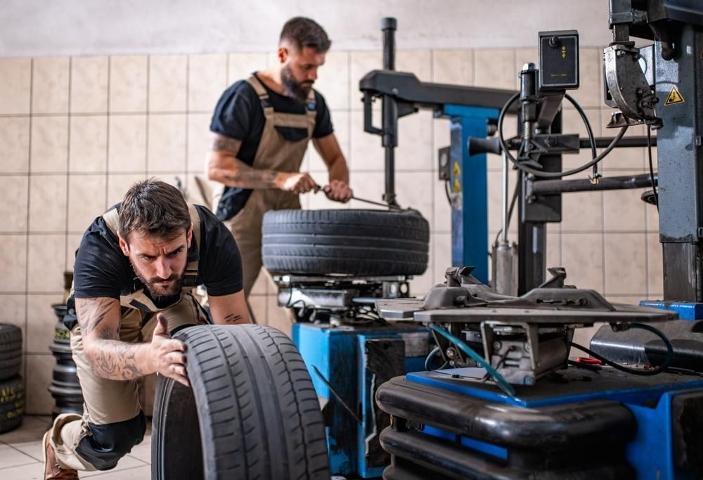 Two Mann Are Working On A Tire In A Garage — Mechanic in Lismore, NSW
