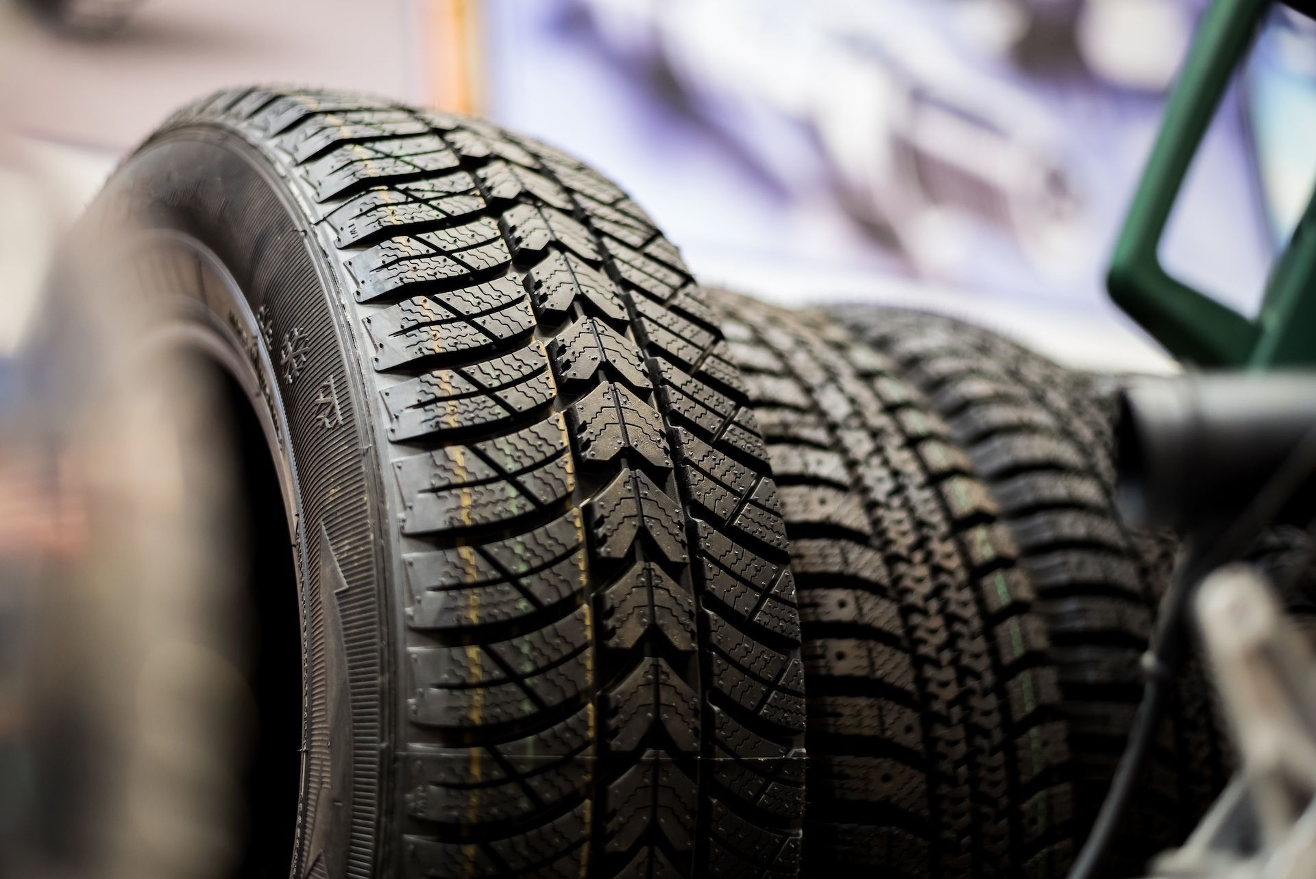 Rows of black car tires with deep tread patterns in a shop display