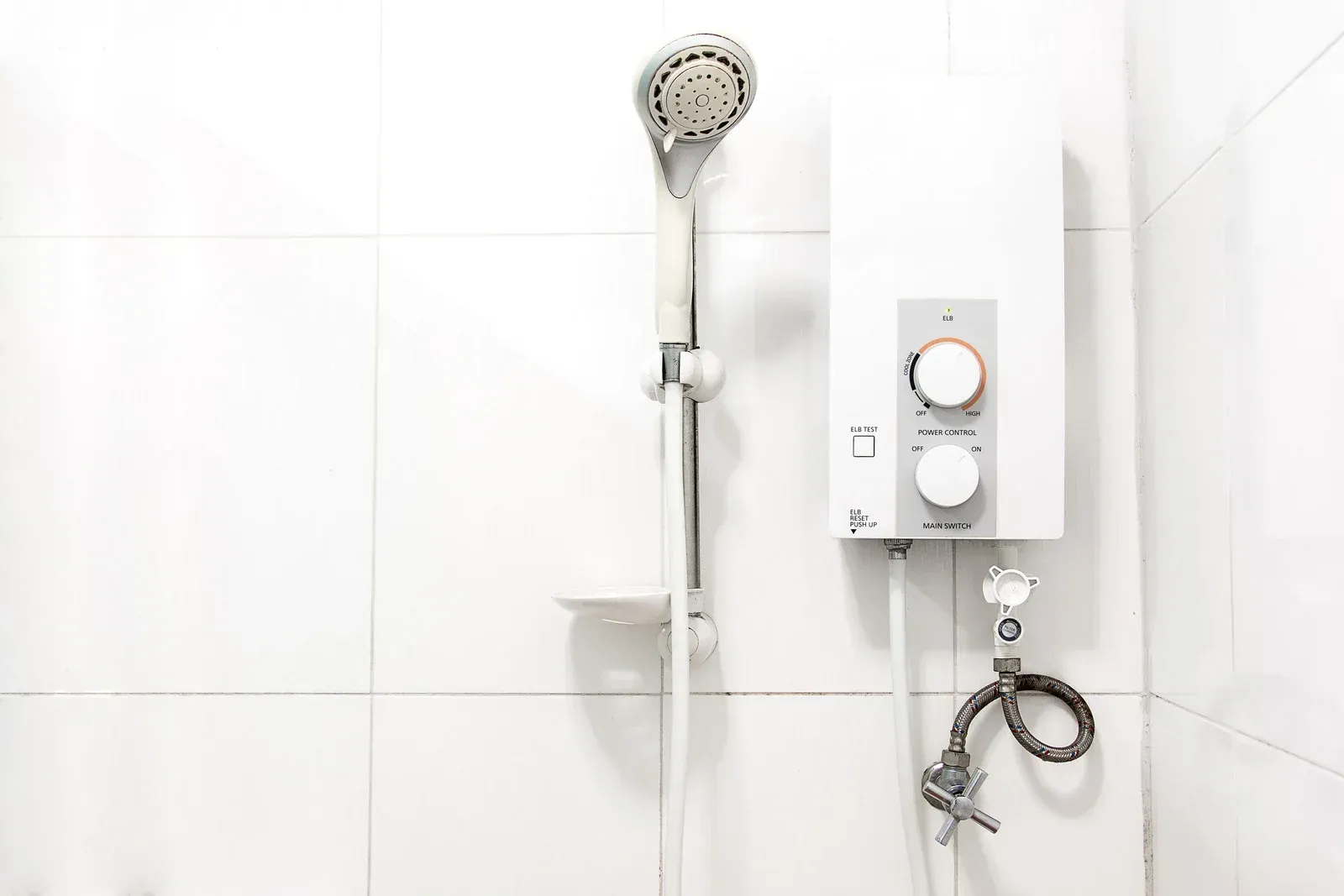 White bathtub with tiled walls in a bathroom, light brown floor, faucet on the side.