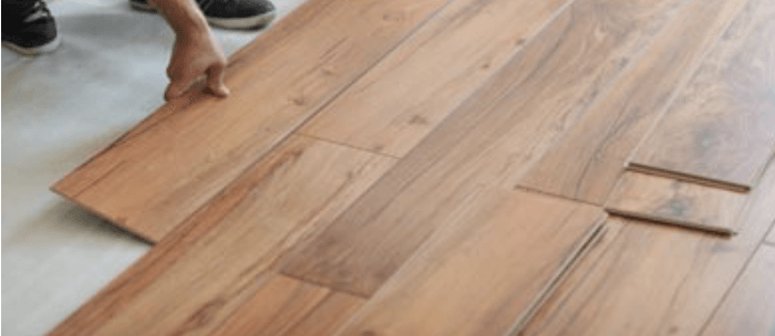 Hand laying wood floor planks, with loose boards and a flooring mallet nearby