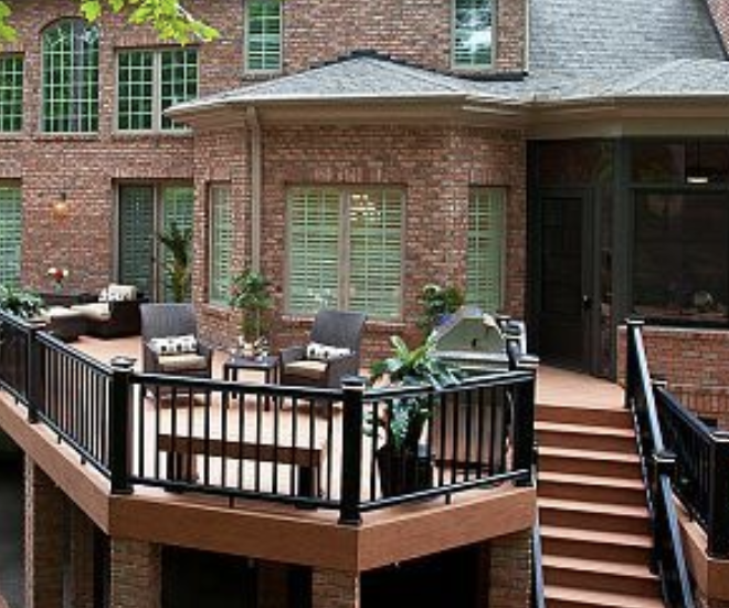 Brick house deck with black railing, patio furniture, and stairs leading down