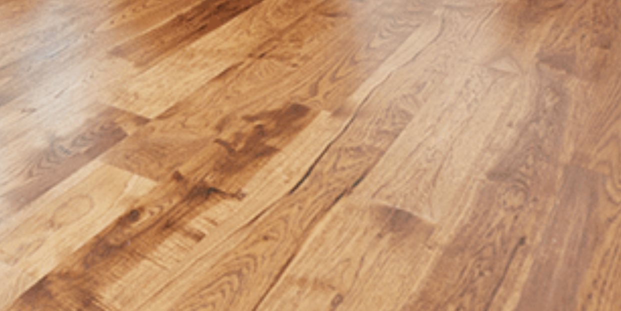 Close-up of polished wooden floor with warm brown grain and sunlight reflections