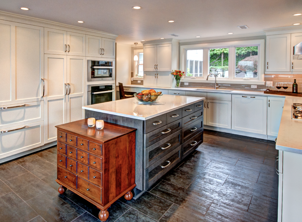 Bright white kitchen with dark wood island, farmhouse sink, and a small rolling wooden cart