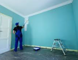 Person painting a turquoise room with a roller, beside a stepladder and paint tray