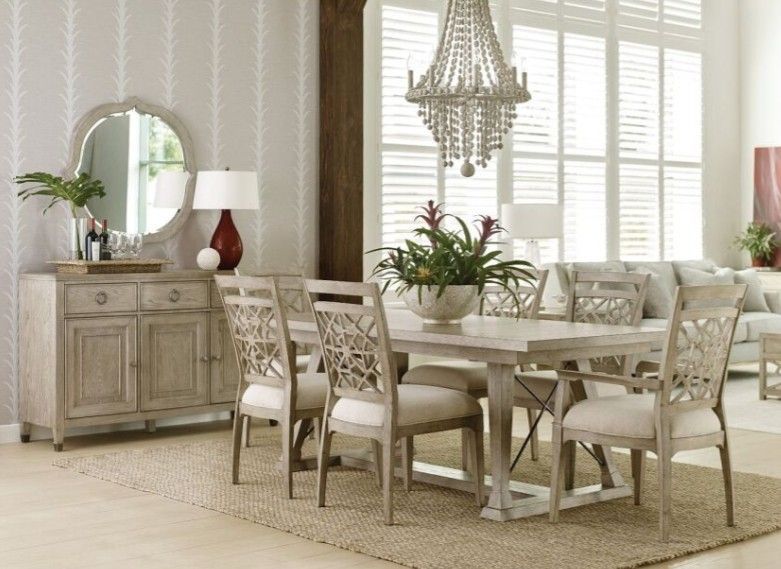 Modern dining room with a wooden table, four upholstered chairs, and a vase centerpiece by a bright window
